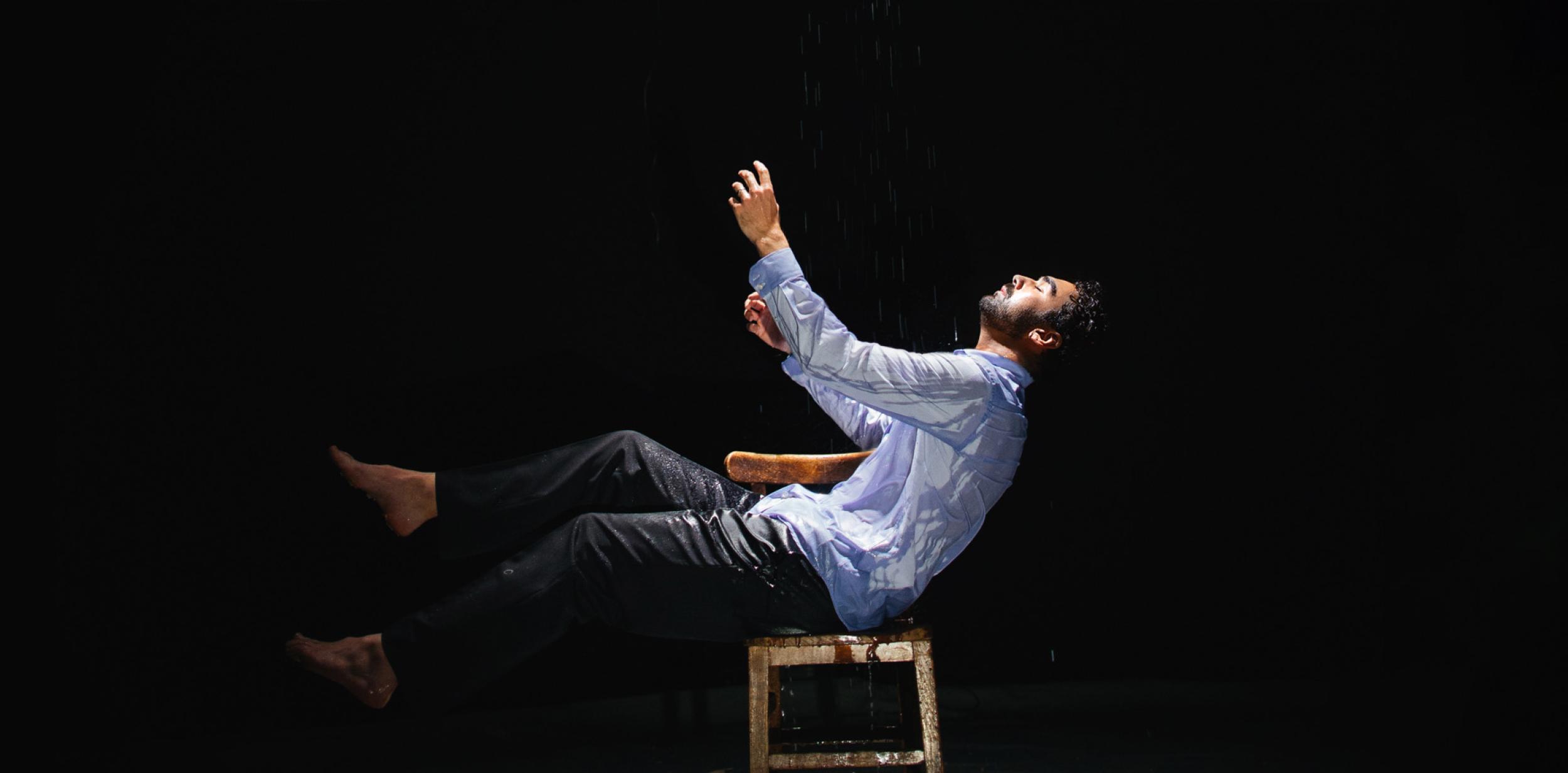 A person leaning back on a chair under a spotlight