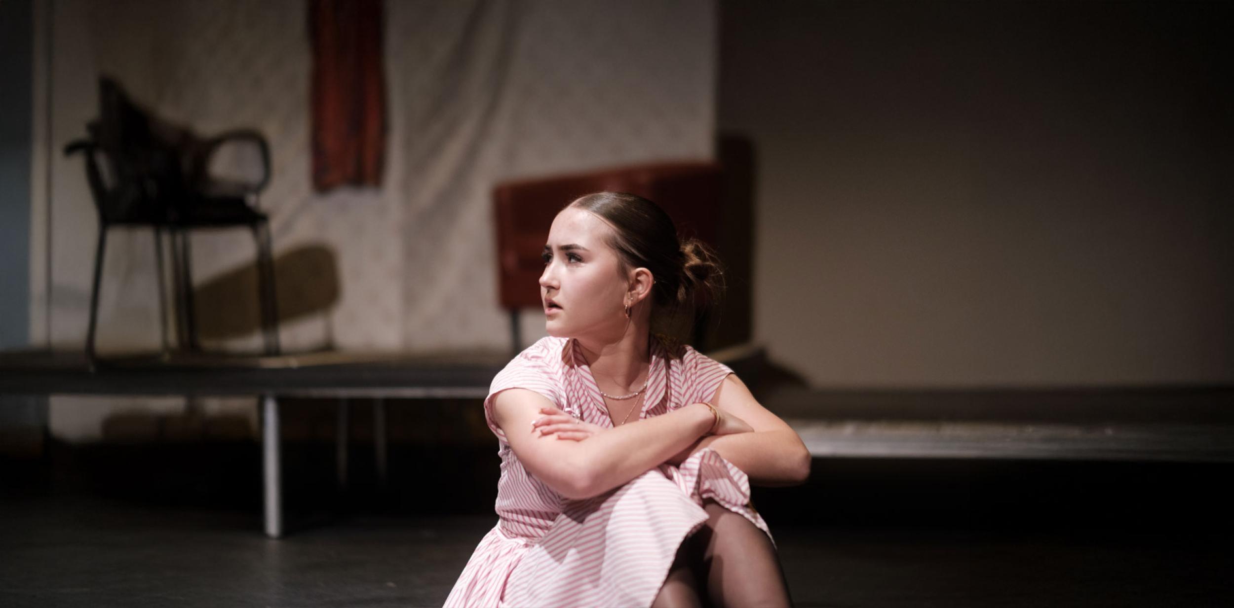 A young person sitting on a stage