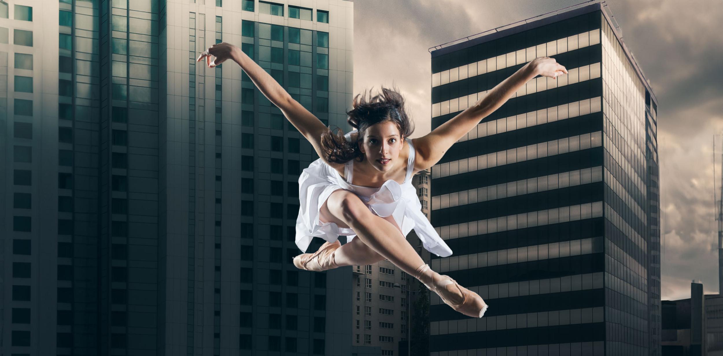 A ballet dancer leaping with skyscrapers in the background