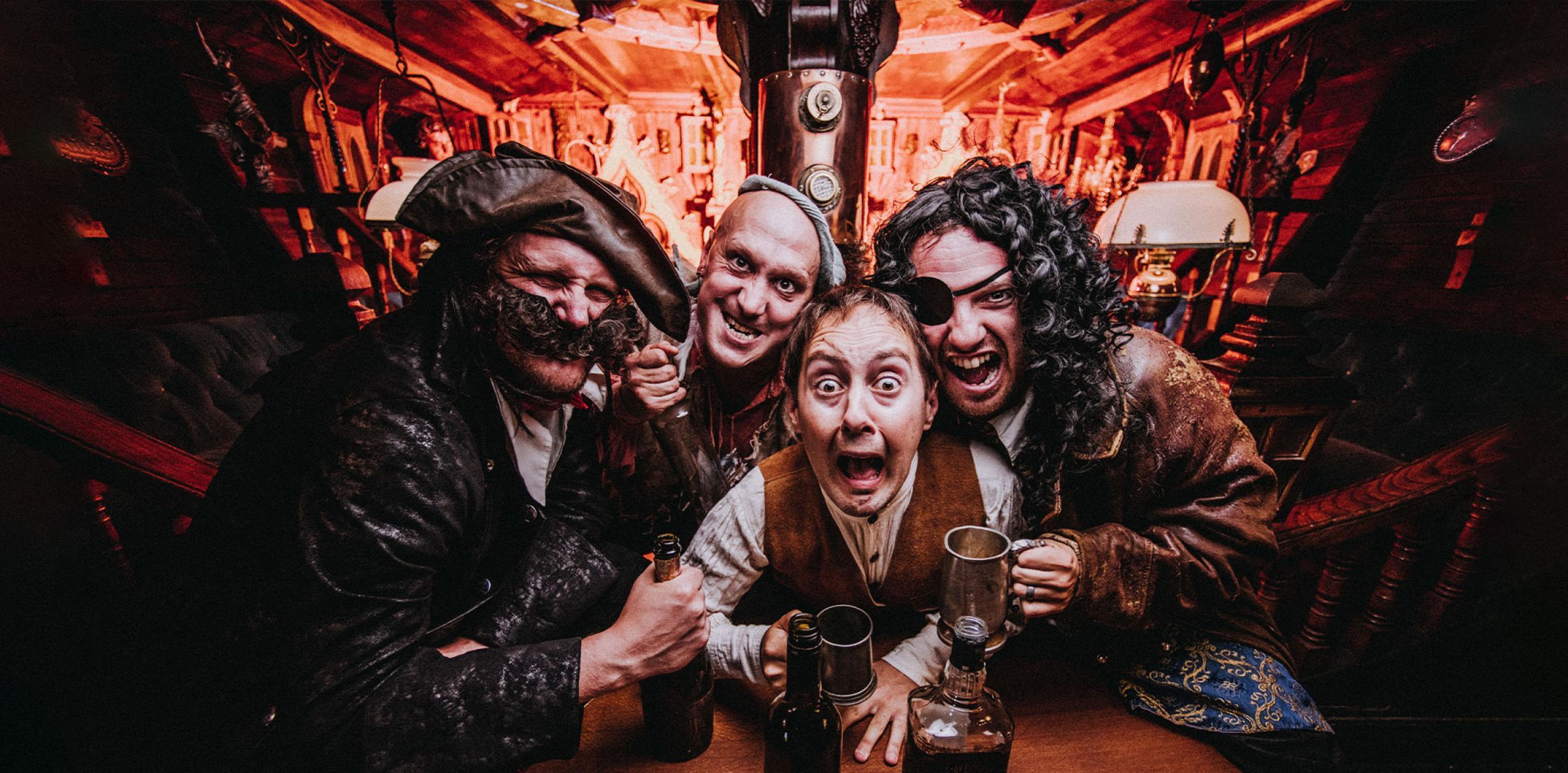 Four pirates drinking grog inside a ship's cabin