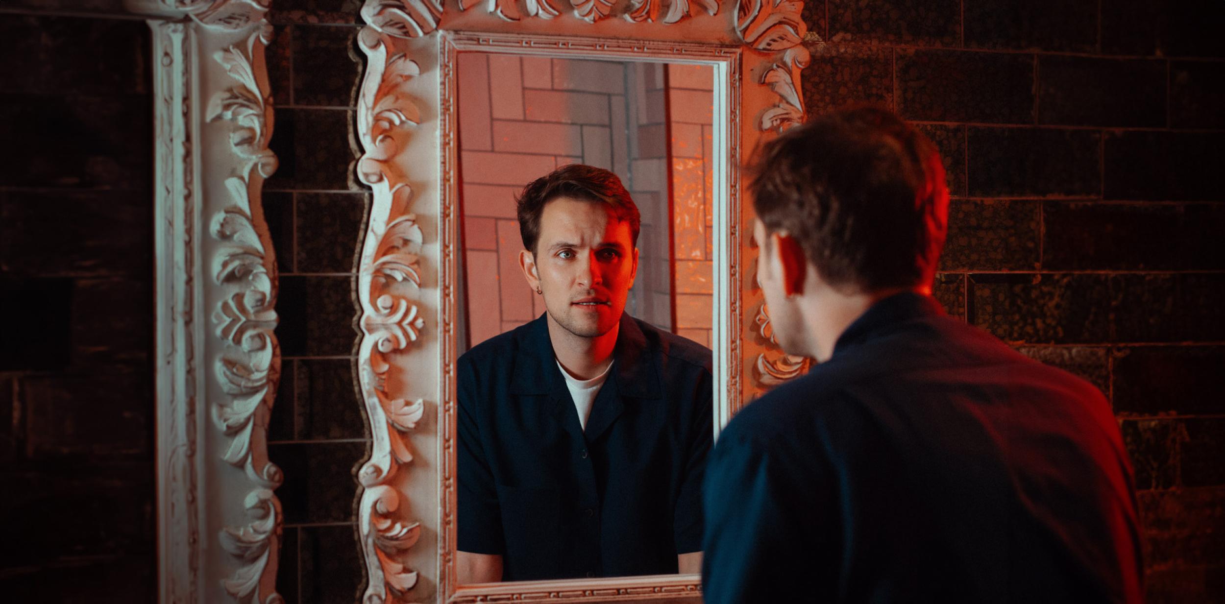 Man looking at reflection through a mirror