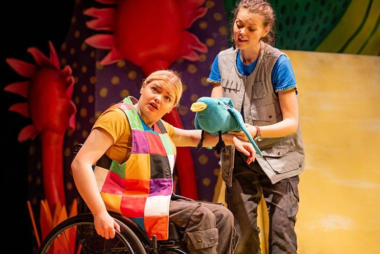 Two performers, one stood with a bird puppet, then other in a wheelchair looking around.