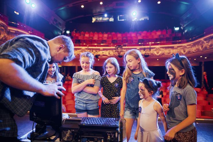 A theatre technician on stage showing children technical elements of a show