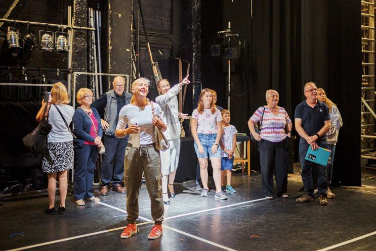 People gather on stage for a backstage stage tour